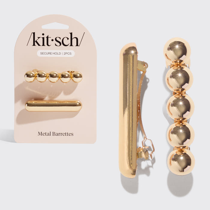 Kitsch metal barrettes set in a shiny gold finish, shown both on the pink retail backing card and as two loose pieces on a light gray background.
