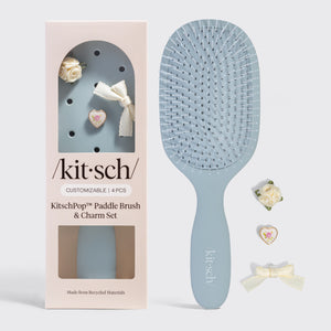 Blue paddle brush with 'kitsch' branding next to its packaging on a gray background