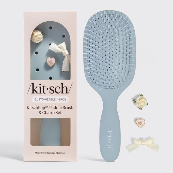 Blue paddle brush with 'kitsch' branding next to its packaging on a gray background